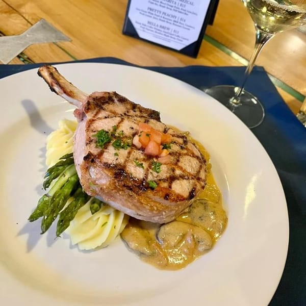 Grilled pork chop with mashed potatoes, asparagus, mushroom sauce, and diced tomatoes at Lago Su Bella.